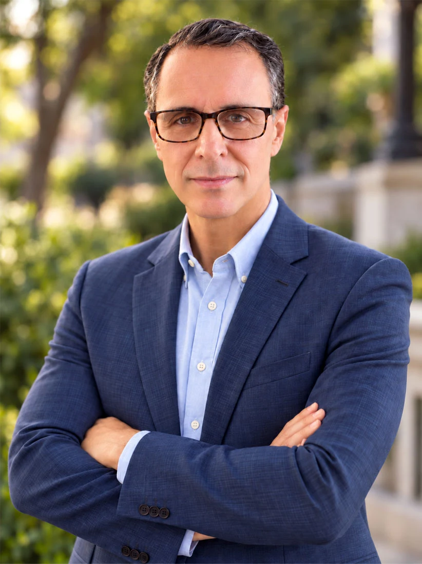 Luis Corredor outdoors wearing glasses and a blue blazer.